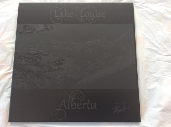laser engraved picture of lake Louise background  on a black ceramic tile.
